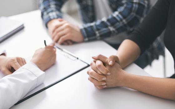 A couple consults with a doctor who is taking notes (Dreamstime/Prostockstudio)